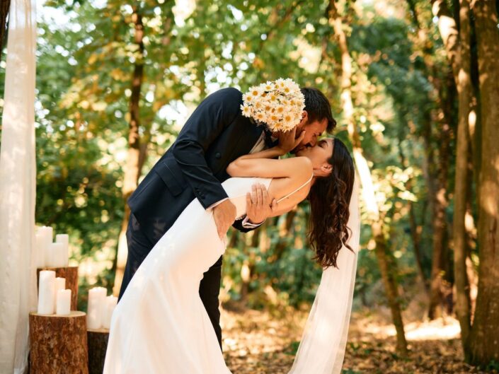 Vőlegény megcsókolja a menyasszonyt az esküvőn a kerti szertartás után