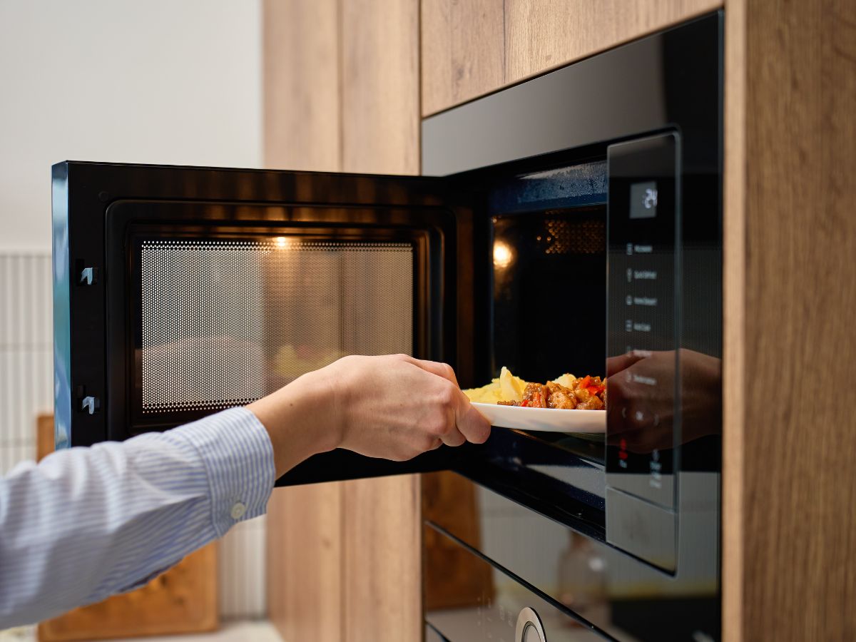 kéz berakja az ételt a mikróba