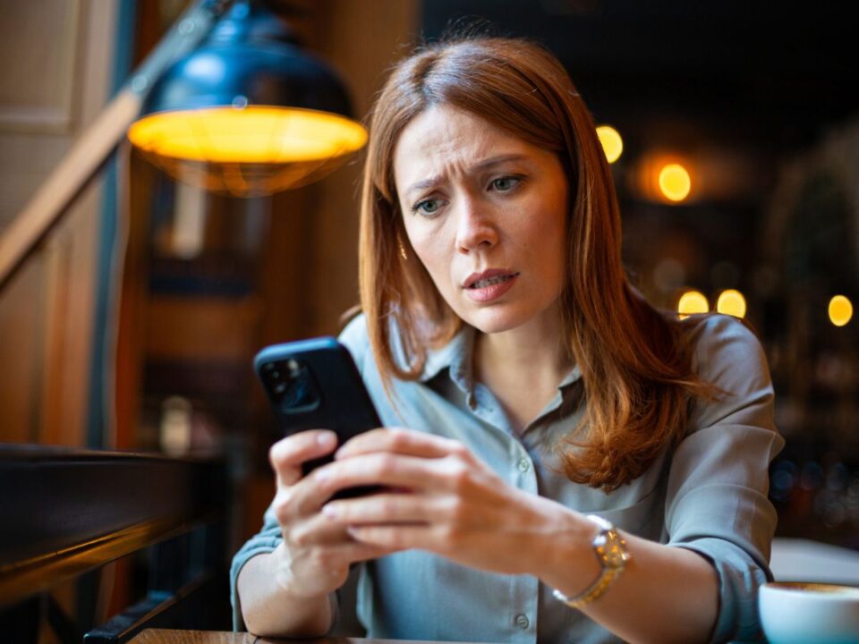 aggódó nő a telefonját nézi