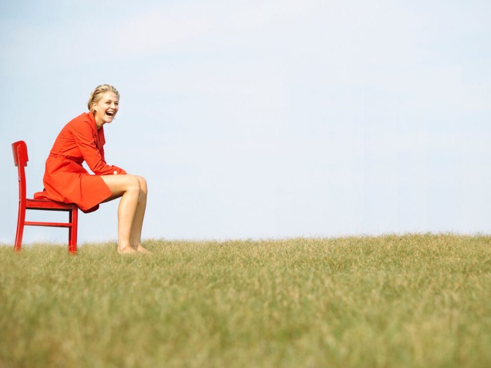 hatvanas-evek-gyerekkor-ritka-kepessegek - Nők Lapja piros ruhán nő piros széken ül a mezőn