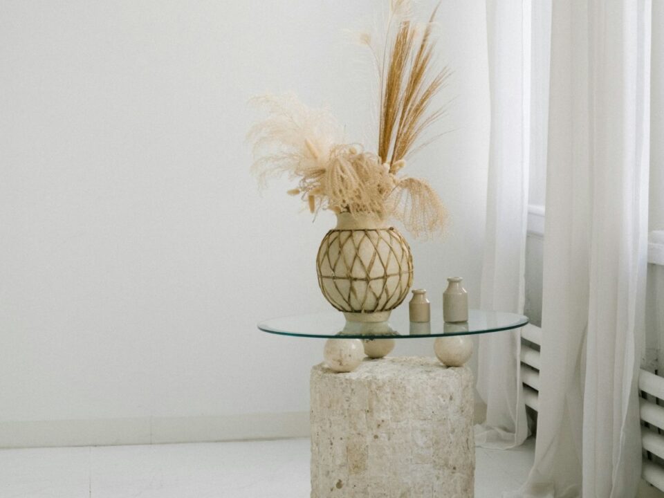 MInimalista, modern enteriőr, kő asztal üveglappal, rajta natúrszínű cserépváza szárított növényekkel