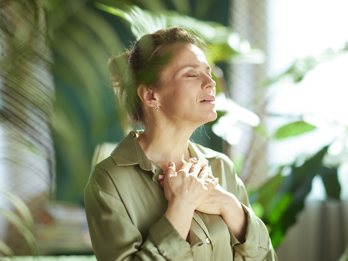 meditatív állapotban lévő zöld ruhás nő áll növények között