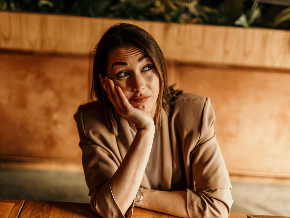 blézeres nő fejét támasztva grimaszol néz