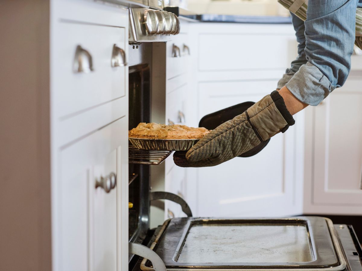 nő kiveszi a süteményt a sütőből
