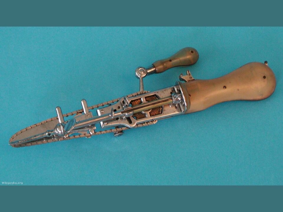 Oszteotóm- Egy régi, kézi hajtású orvosi eszköz látható kék háttéren; fém szerkezet, fogazott lánccal és fa markolattal, a korai sebészeti láncfűrész elődje.