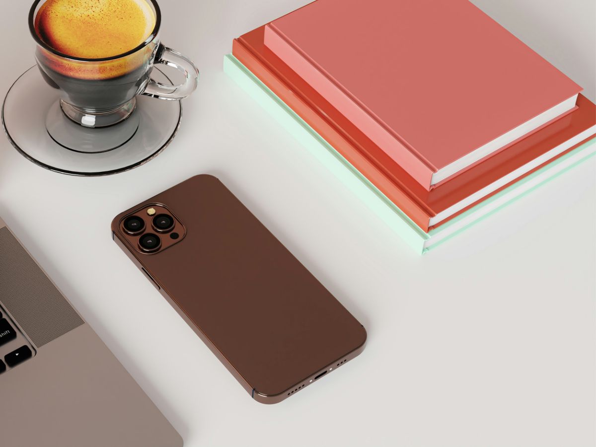 Lefordított telefon fehér asztalon jegyzetfüzetek és egy pohár fekete kávé mellett