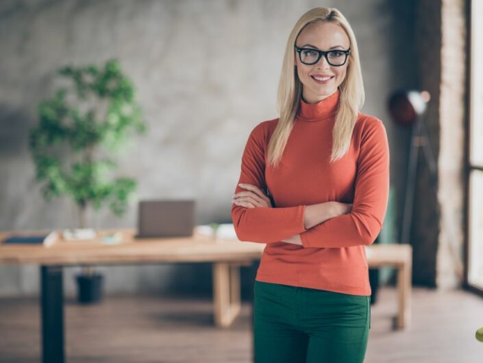 szőke szemüveges nő áll az irodájában