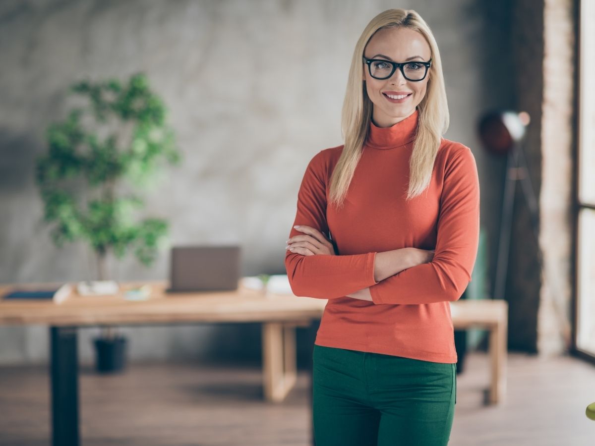 szőke szemüveges nő áll az irodájában