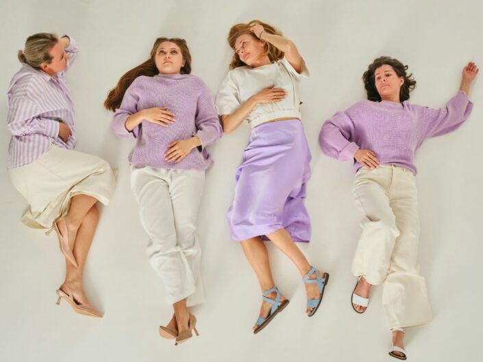 Négy középkorú nő a padlón fekszik lila-fehér szettben