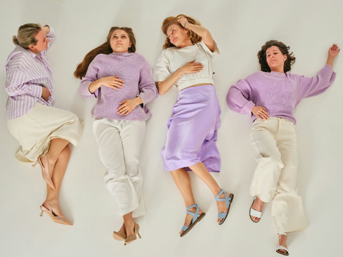 Négy középkorú nő a padlón fekszik lila-fehér szettben