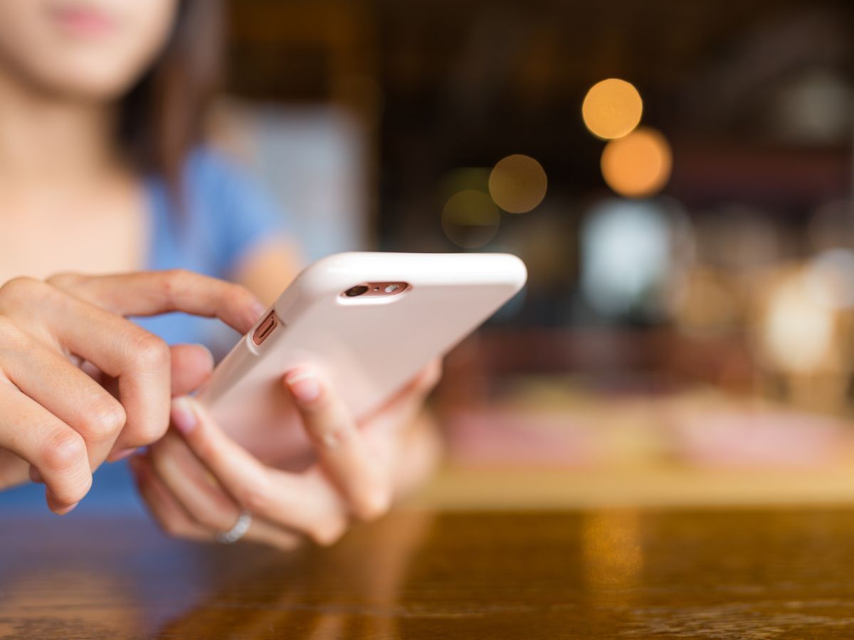 nő mobiltelefont tart a kezében