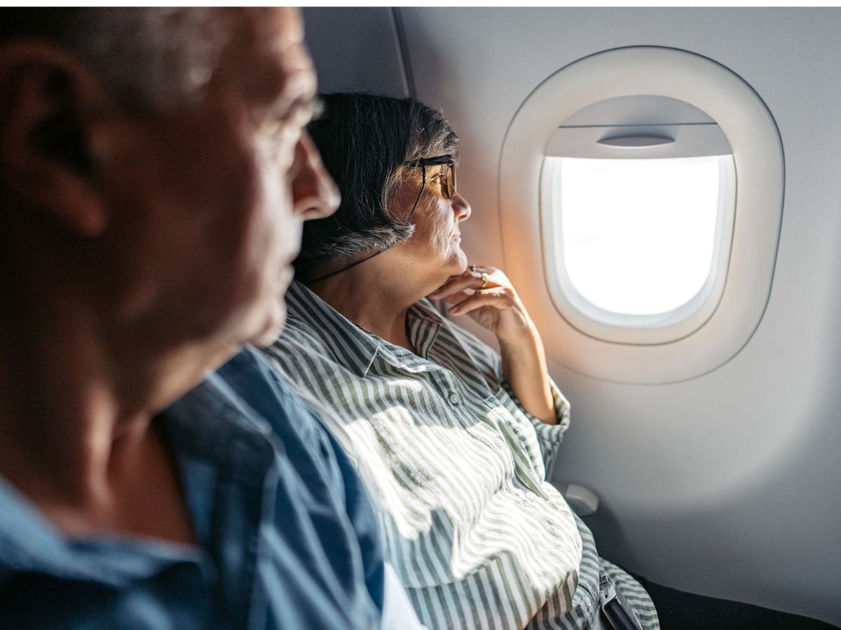 idős pár a repülőn néz ki az ablakon