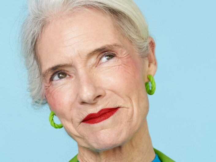 Szép 50 feletti nő piros rúzzsal mosolyogva néz fel oldalra közeli képen