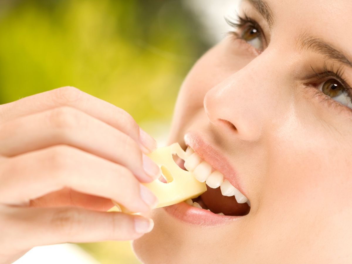 Nő közeli képen sajtot tesz a szájába