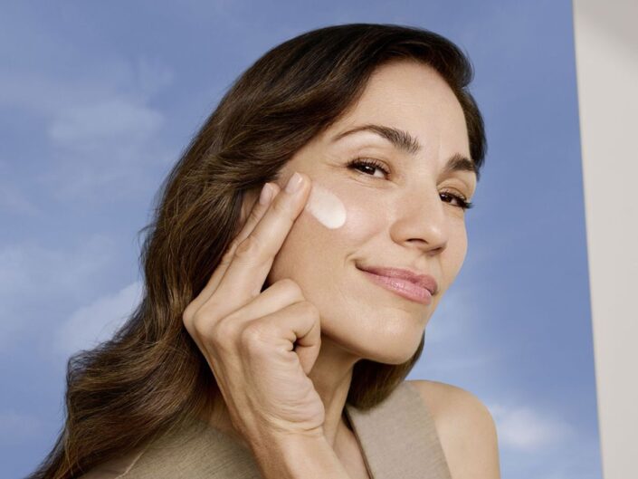 barna hajú középkorú nő krémezi az arcát