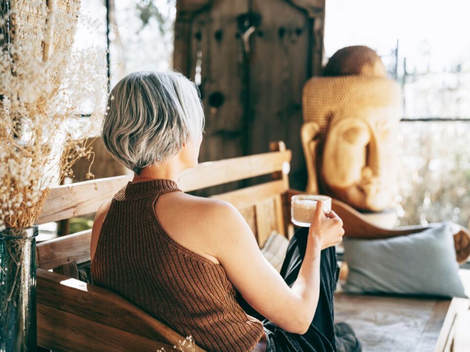 egy középkorú nő relaxál egy padon és habos kávét fog a kezében