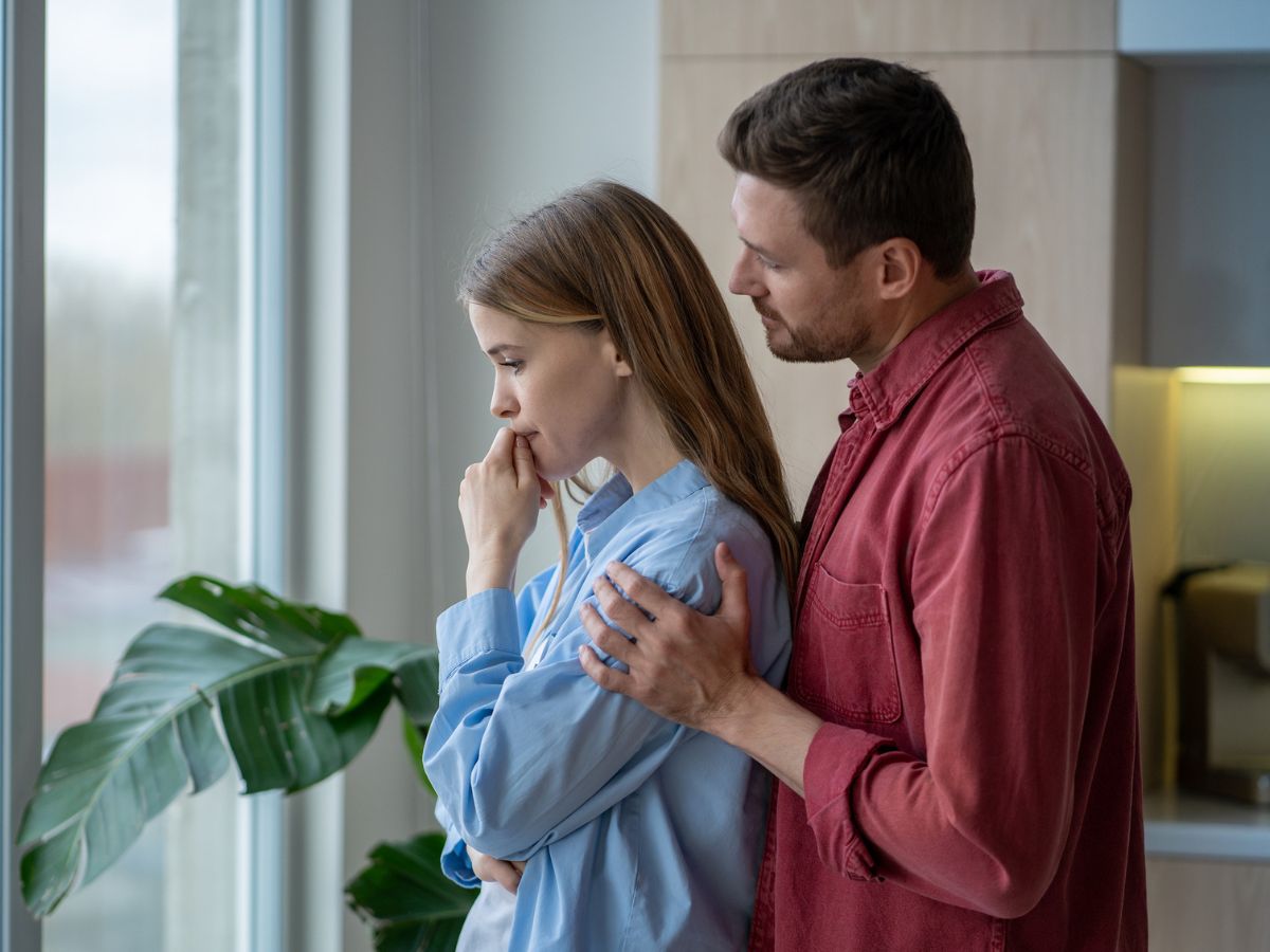 szomorú pár áll az ablaknál