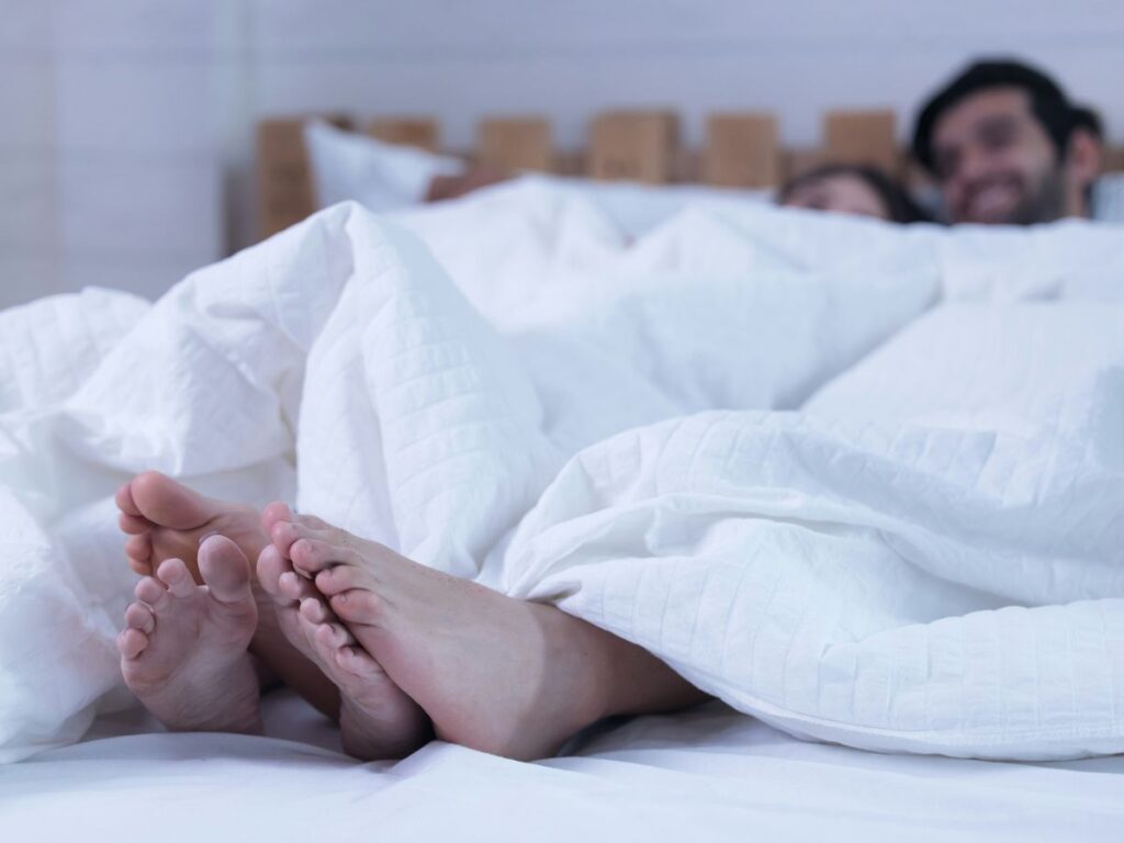 Pár ágyban, fókusz a takaró alatt összeérő lábakon