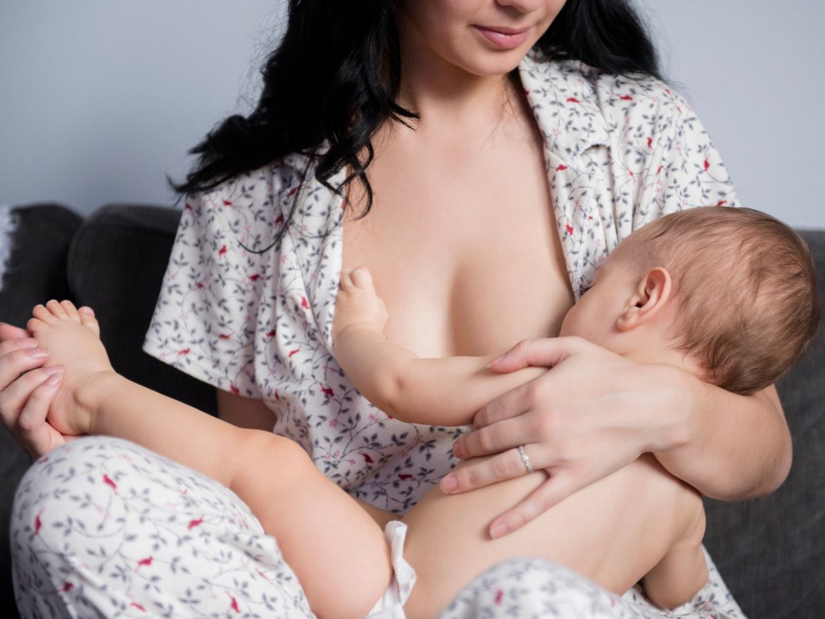 Nő pizsamában nagyobb gyereket szoptat