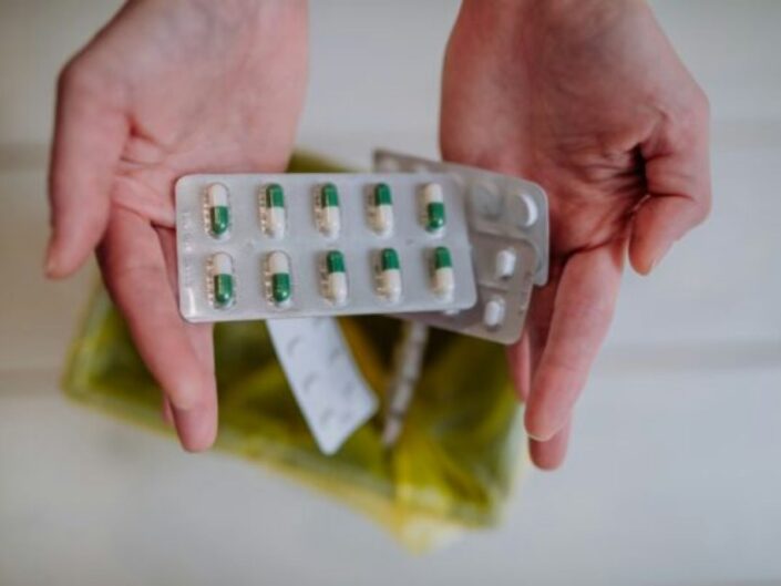 Nő a kezében tart allergia elleni gyógyszereket a szemetes felett, majd egyenként beleejti