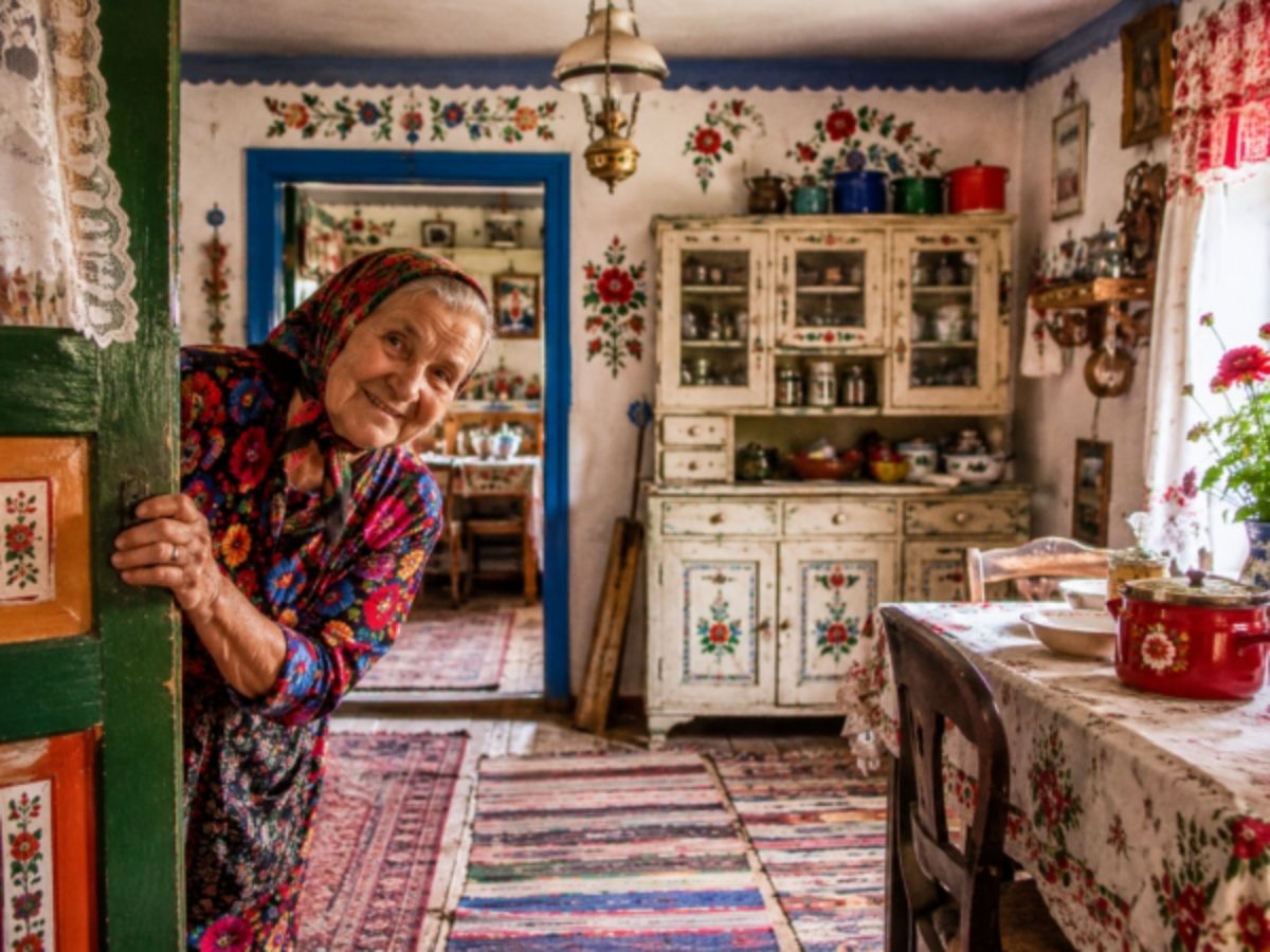 régi korok fejkendős nagymamája mosolyog a kredenc előtt