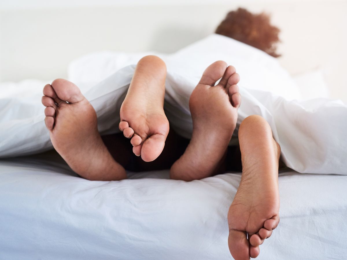 pár ágyban takaró alatt szex közben, a lábak felől fotózva