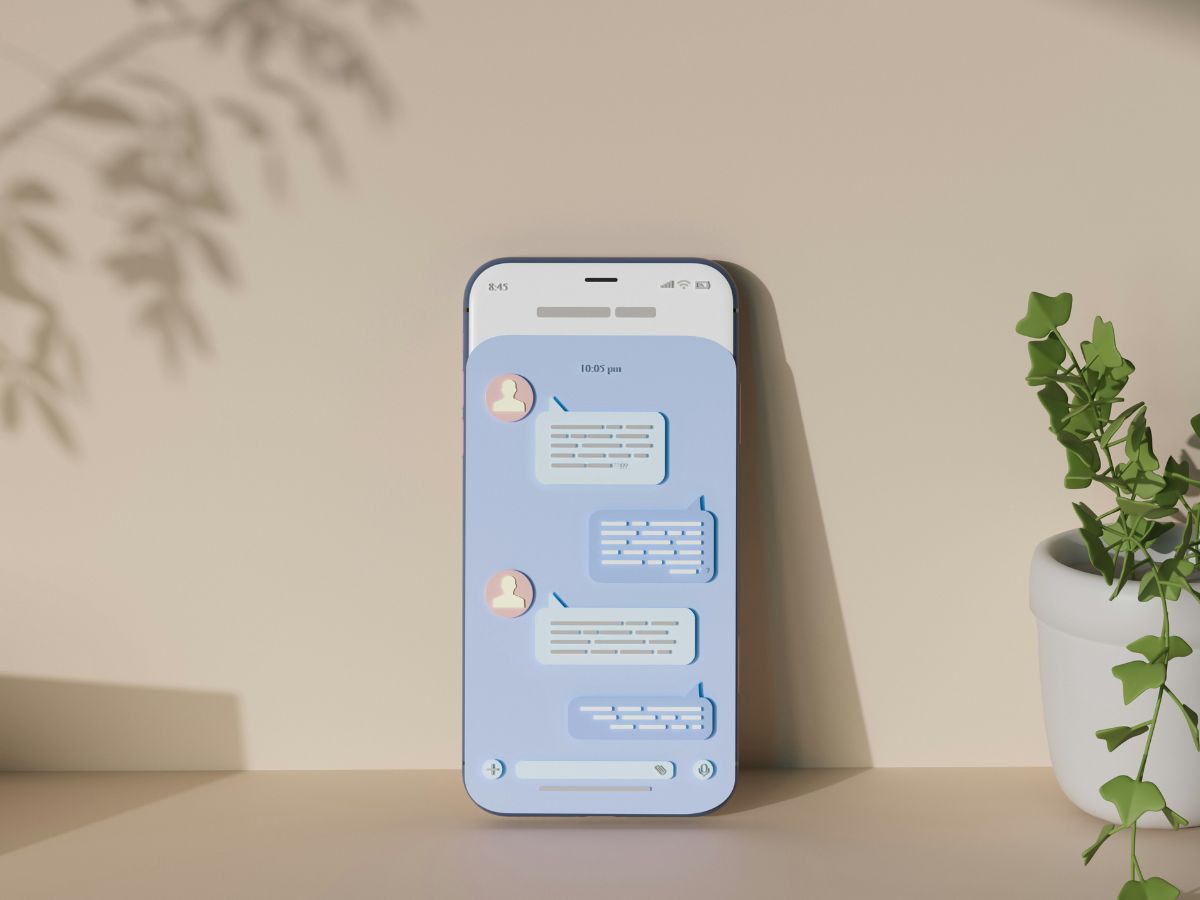 Illusztráció falhoz támasztott telefonról, neutrális kék kijelzőn szöveges üzenet koncepciója, bézs hangulatú képen, egyik oldalon szobanövény, másikon növény árnyéka a falon