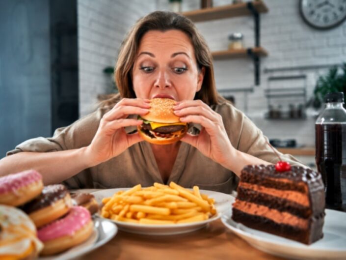 nő hamburgert eszek előtte tálon sült krumpli és édességek