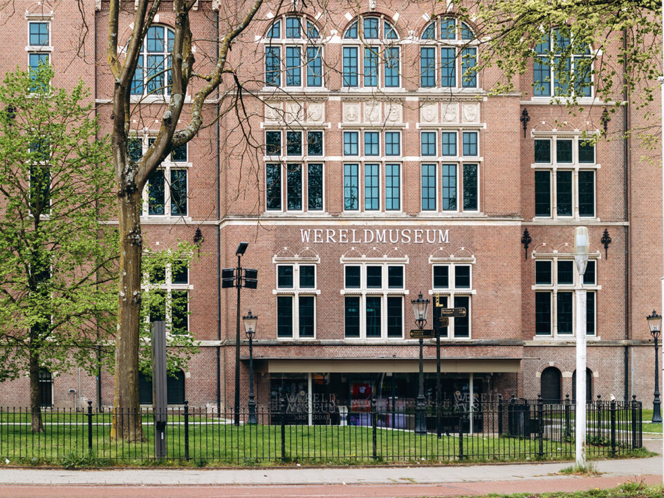 Exterior view of the Wereldmuseum Amsterdam featuring historic brick architecture and spring trees in Amsterdam - Nők Lapja