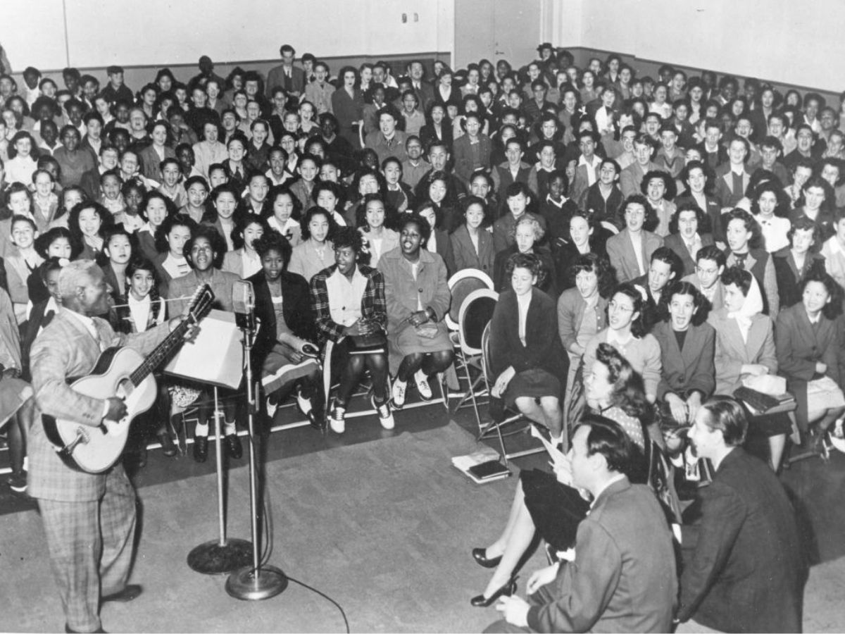 Lead Belly jazz zenész gitárral, körülötte a hallgatóság, 1949-ben