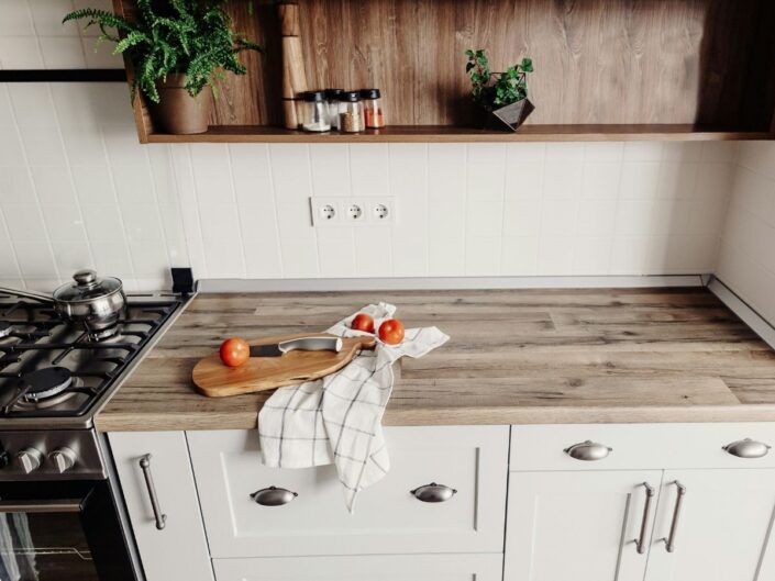 Modern konyha fa konyhapulttal fehér konyhaszekrényen, rajta vágódeszka, paradicsomok és konyharuha