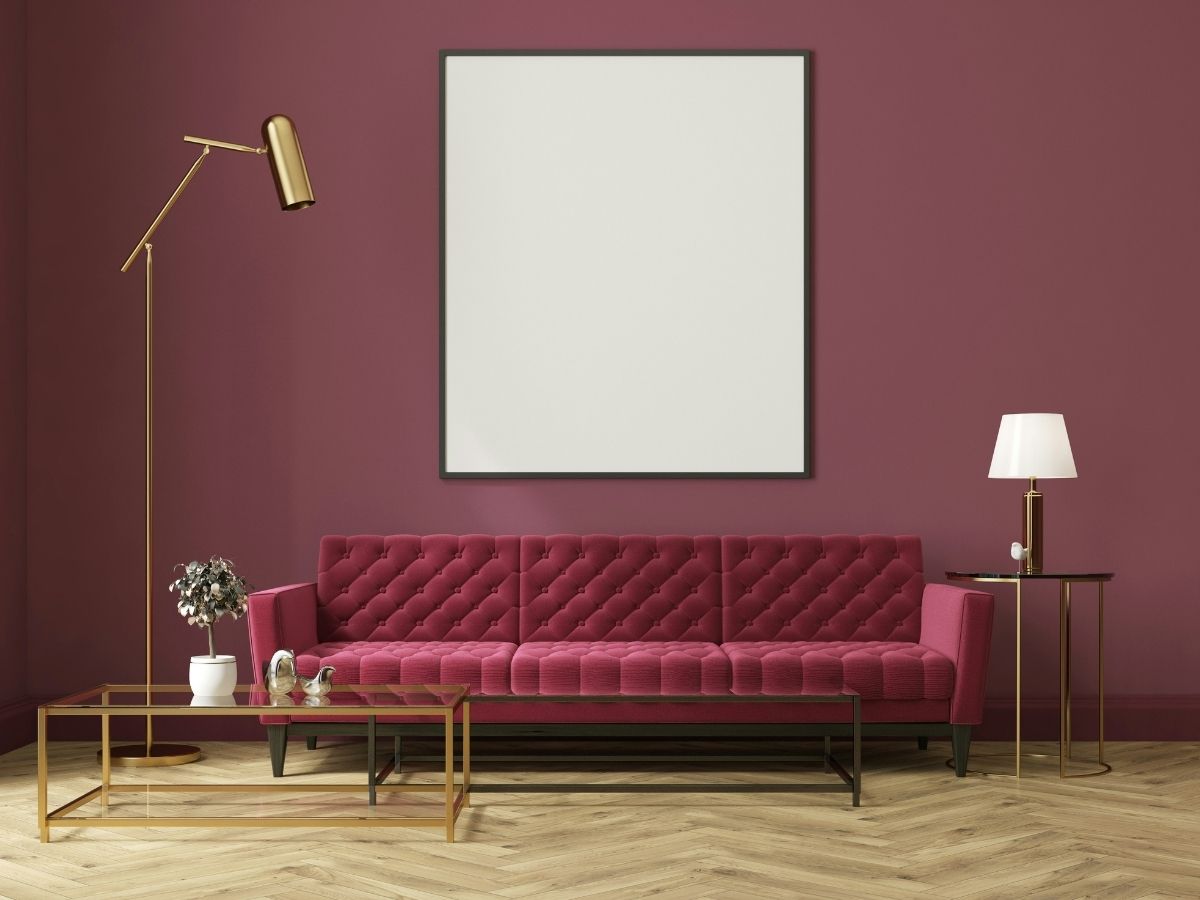 1. A sötétlila egyszerre elegáns és nyomasztó - Nők Lapja Sötétlila fal, fehér kép, padlizsánszínű bársonykanapé dohányzóasztallal elegánsan berendezett nappaliban