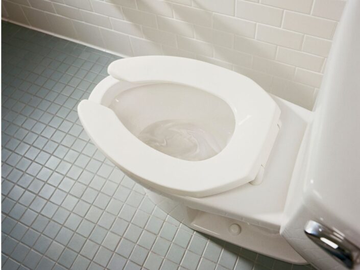 fehér csempés fürdőszoba elöl nyitott wc-ülőkés vécével
