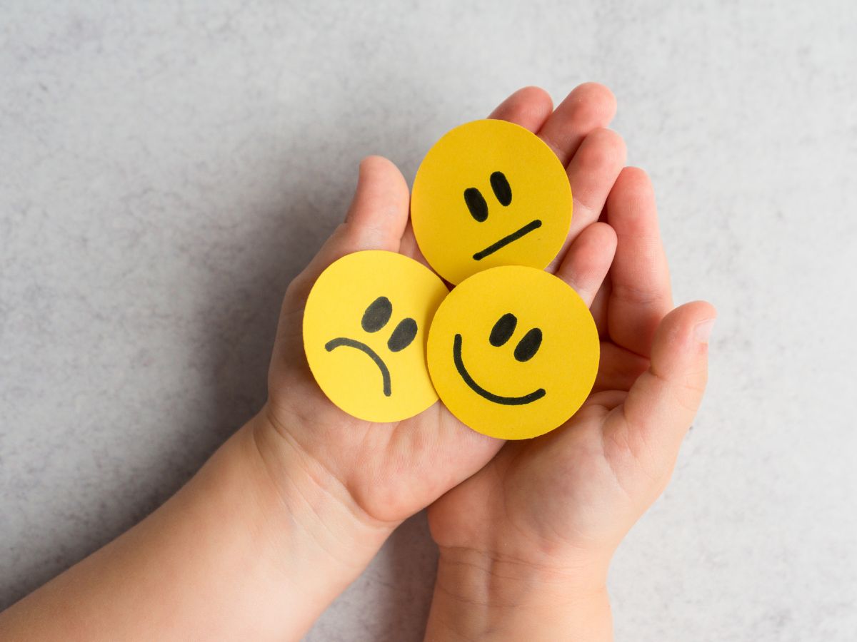 két tenyér felfelé néz rajtuk három smiley korong különböző arckifjezésekkel