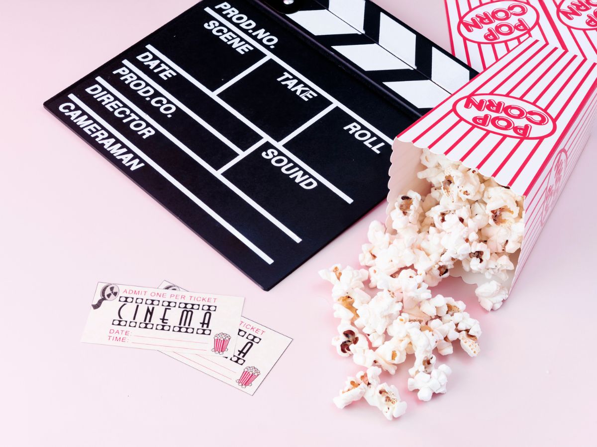 csapó, mozijegyek és popcorn rózsaszín háttér előtt