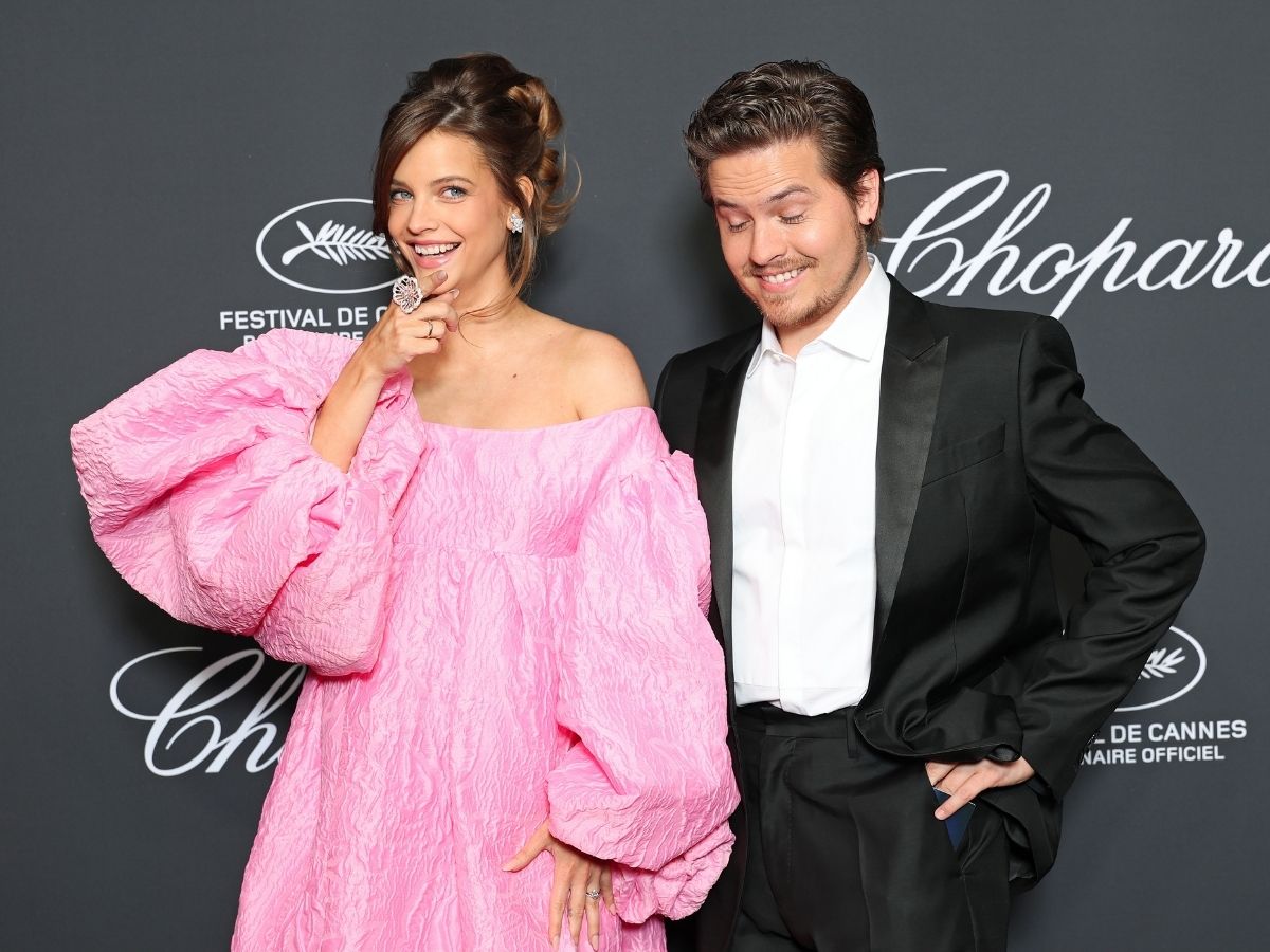 Palvin Barbara rózsaszín várandós estélyi ruhában játékosan mutat a kamerába, mellette nevetve áll fekete szmokingban férje, Dylan Sprouse