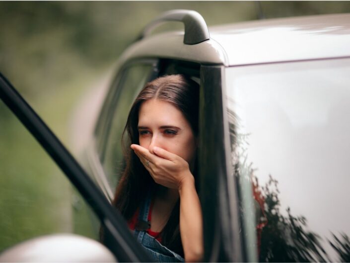 Nőnek hányingere lett autózás közben, nyitott ajtajú autóban ül parkolóban