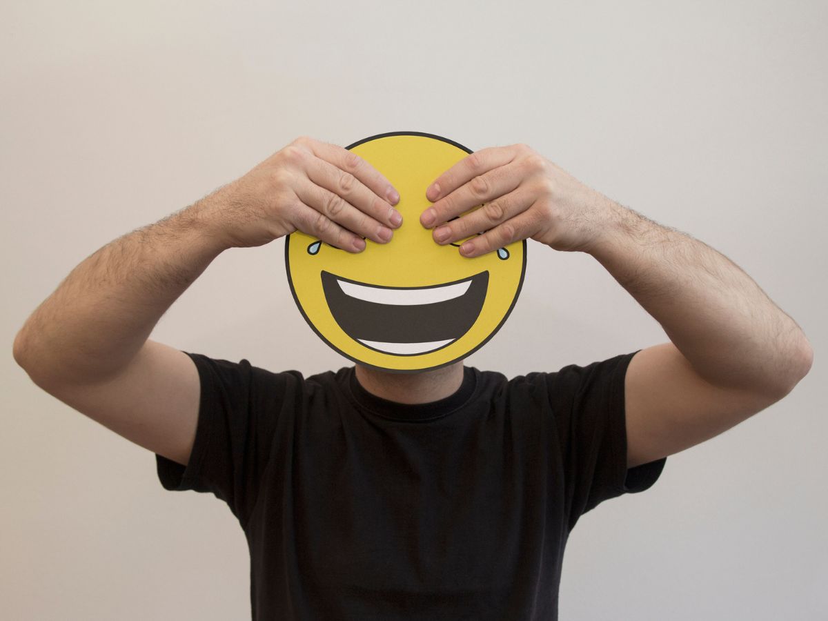 Férfi, aki egy papír emojival takarja el az arcát