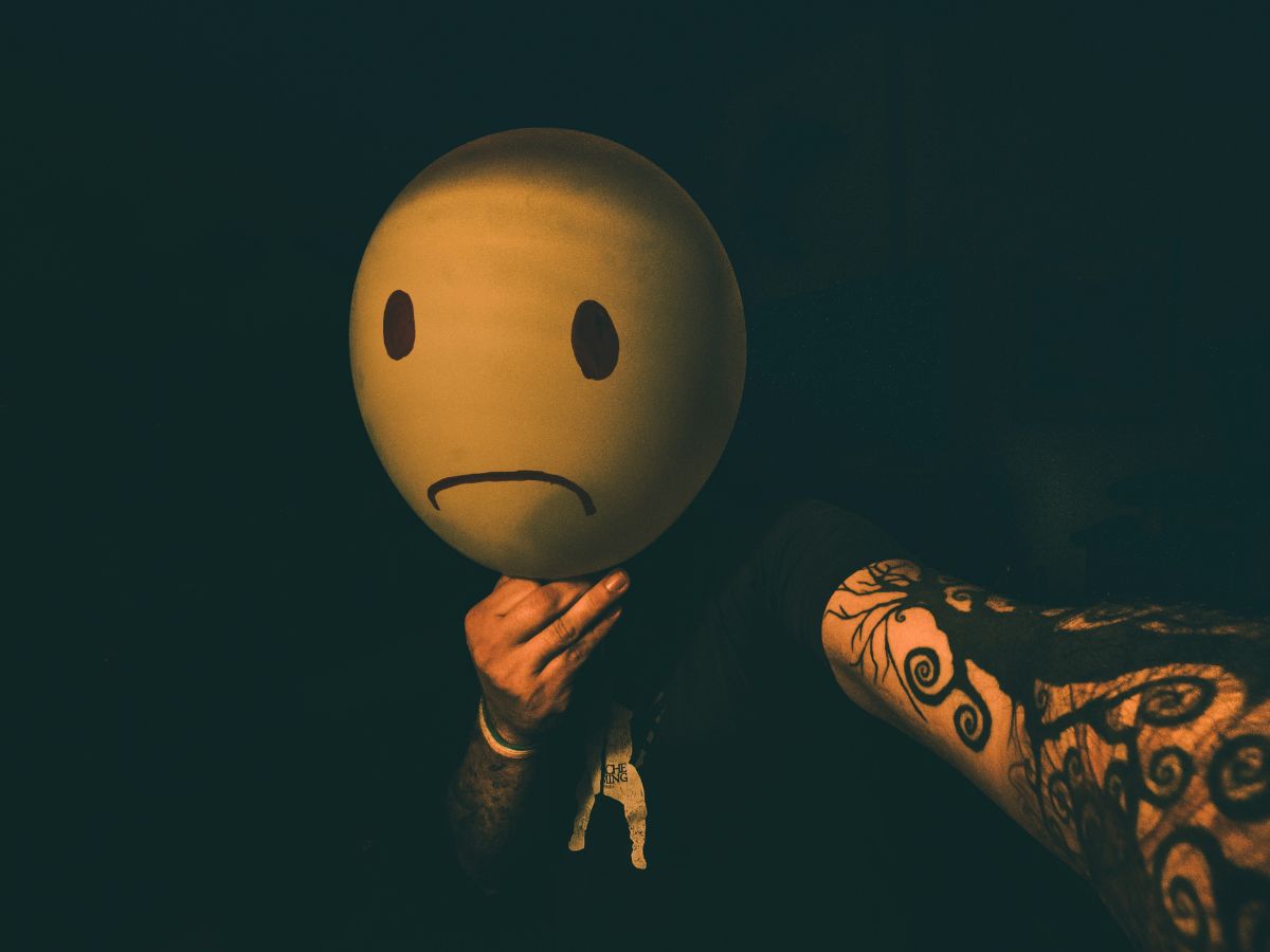 rosszkedvű ember szomorú emojival az arca előtt