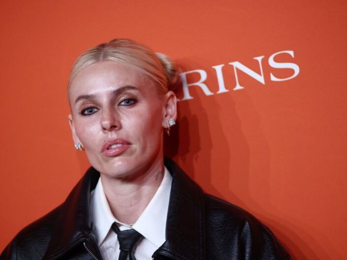 Lauren Wasser modell fekete öltönyben, fekete nyakkendővel hátrakötött hajjal bemutatón