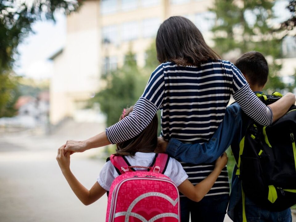 szuloseg-gyerekneveles-tisztelet - Nők Lapja anyuka és két gyereke egymást átölelve mennek az iskolába