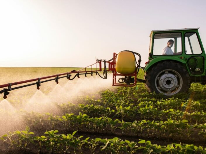 Traktor naplemente aranyórájában vegyszerrel permetez termőföldön