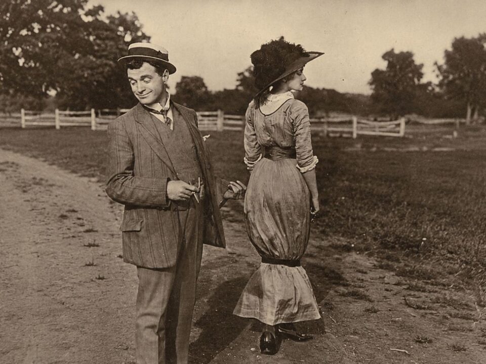 Nő hobble skirt-ben, a balesetveszélyesen szűkített szoknyában és férfi áll földúton az 1910-es években
