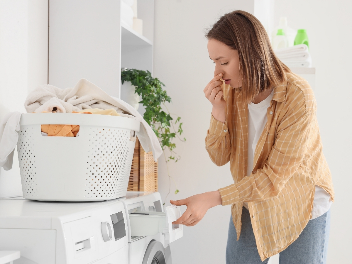 - Nők Lapja Nő orrát befogva szagolja a mosógép tálkáját, miközben kihúzza, a mosógép tetején ruháskosár