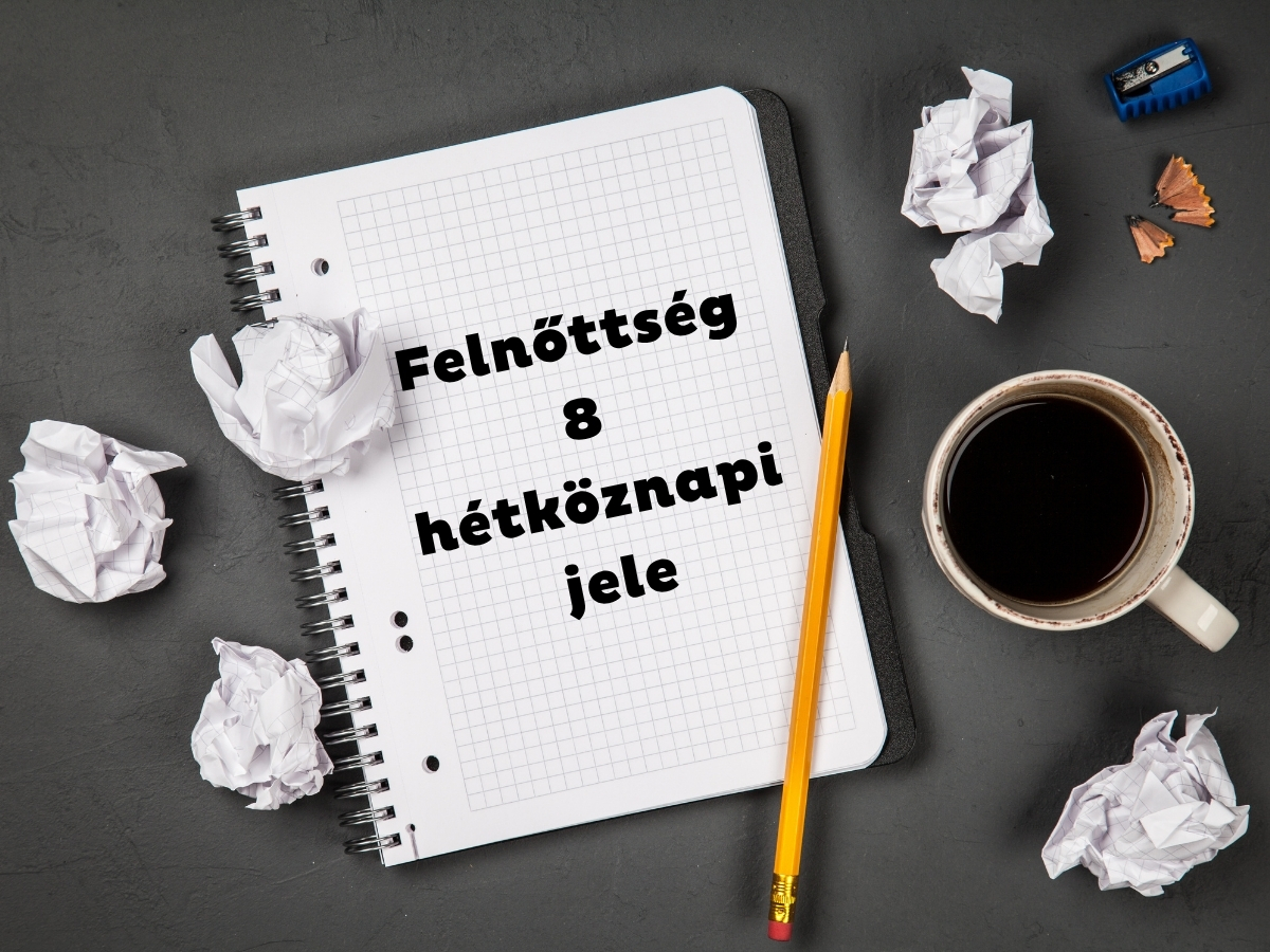 Fekete háttér, spirálfüzet, összegyűrt papírlapok, ceruza és csésze kávé felülről fotózva