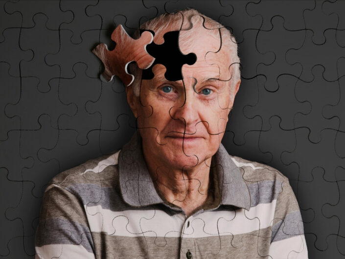 Idős férfi szürke háttér előtt, puzzle vonalakkal, fejének egyik része elmozdítva a kirakósban