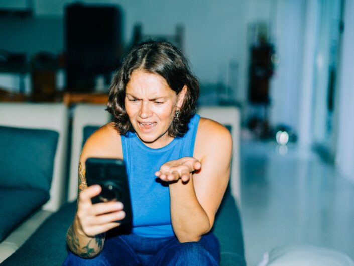 nő mérgesen nézi a telefon kijelzőjét