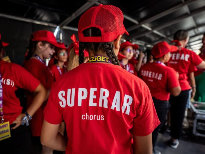 A Superar kórusának tagjai piros pólóban és baseballsapkában a Sziget Fesztivál színpadán