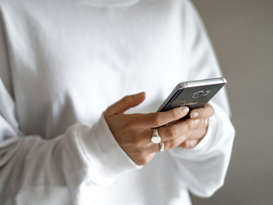 sms-csalas - Nők Lapja Nő fehér pulóverben telefonján gépel